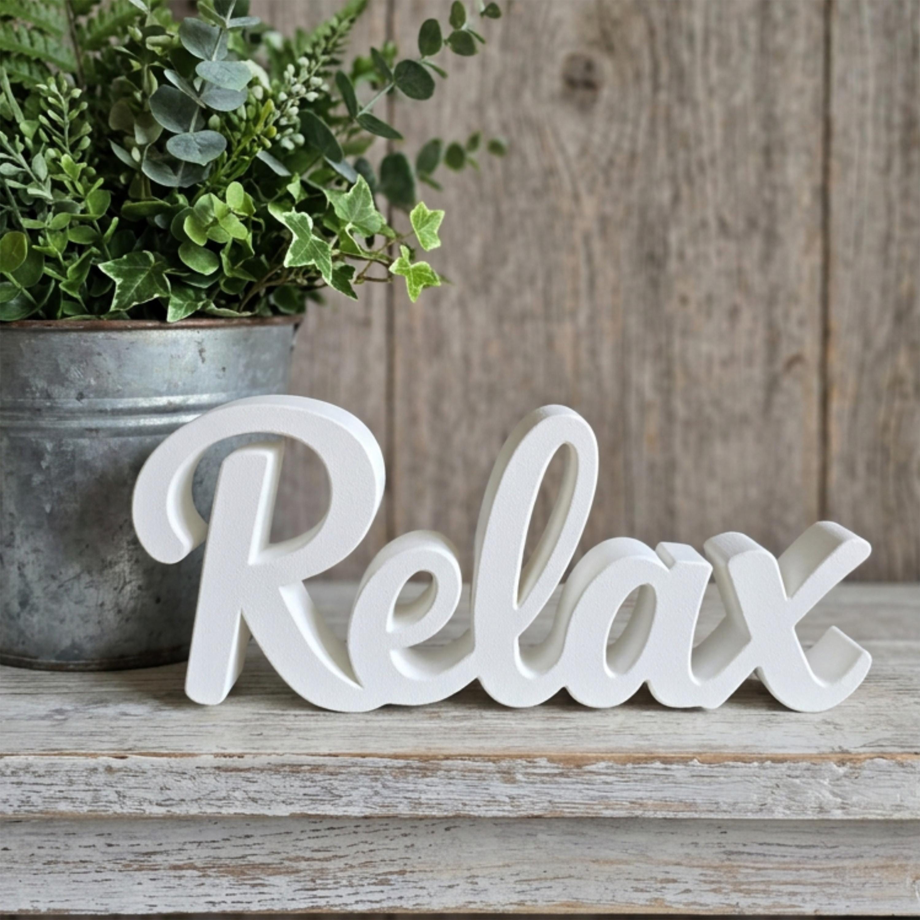 White Relax sign on wooden surface with potted plant – minimalist bathroom decor, made in USA